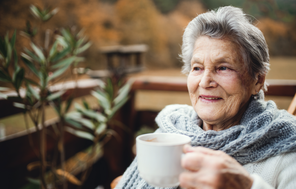 Senior woman with cup, reflecting on social isolation during COVID-19