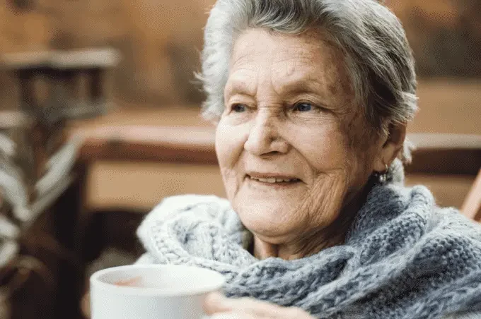 Senior woman with cup, reflecting on social isolation during COVID-19
