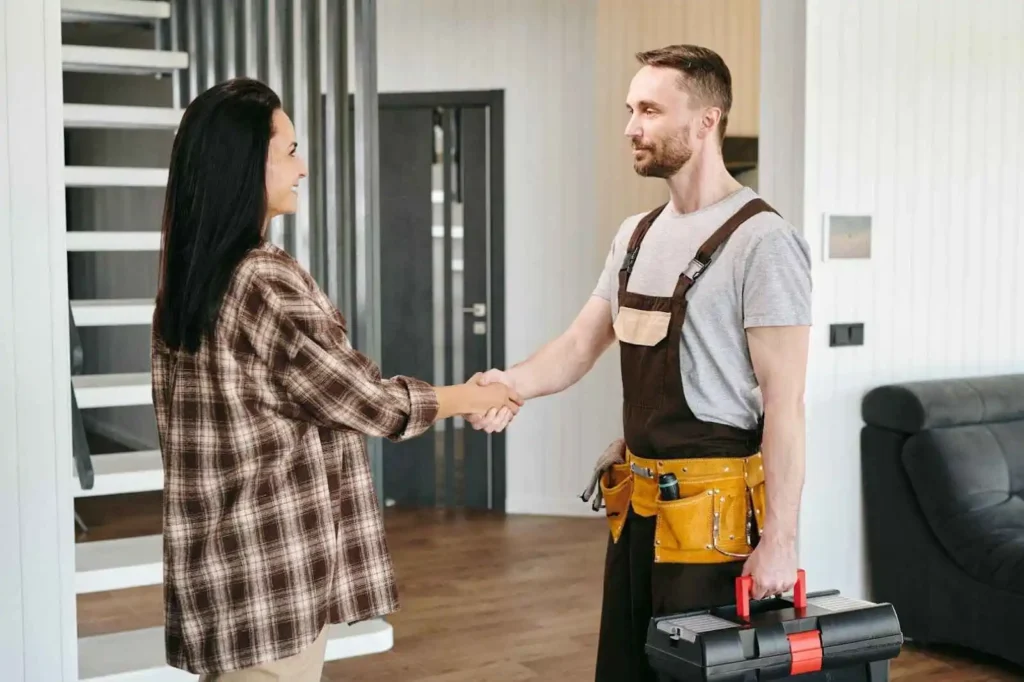 Woman shaking hands of handyman after work