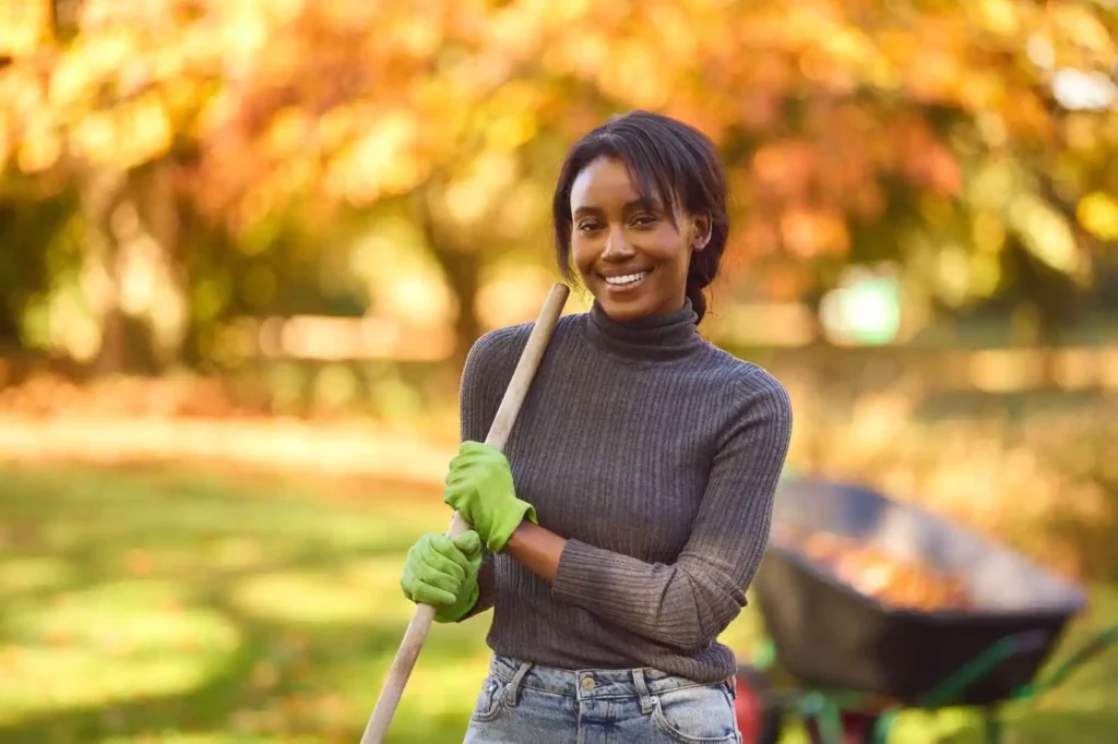 Young Woman With Barrow Raking Leaves