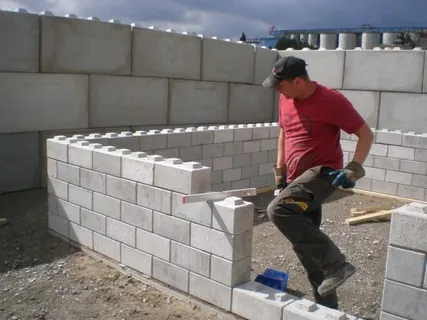Handyman worker laying concrete blocks in yard