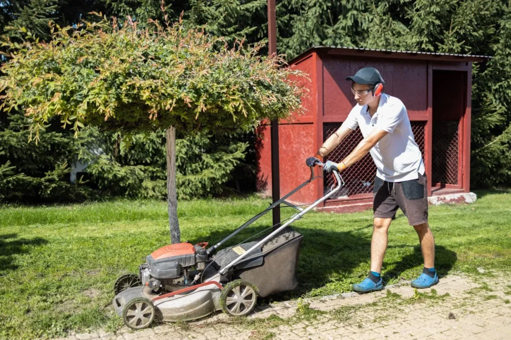 Gardener mowing the grass with a gasoline lawn mower