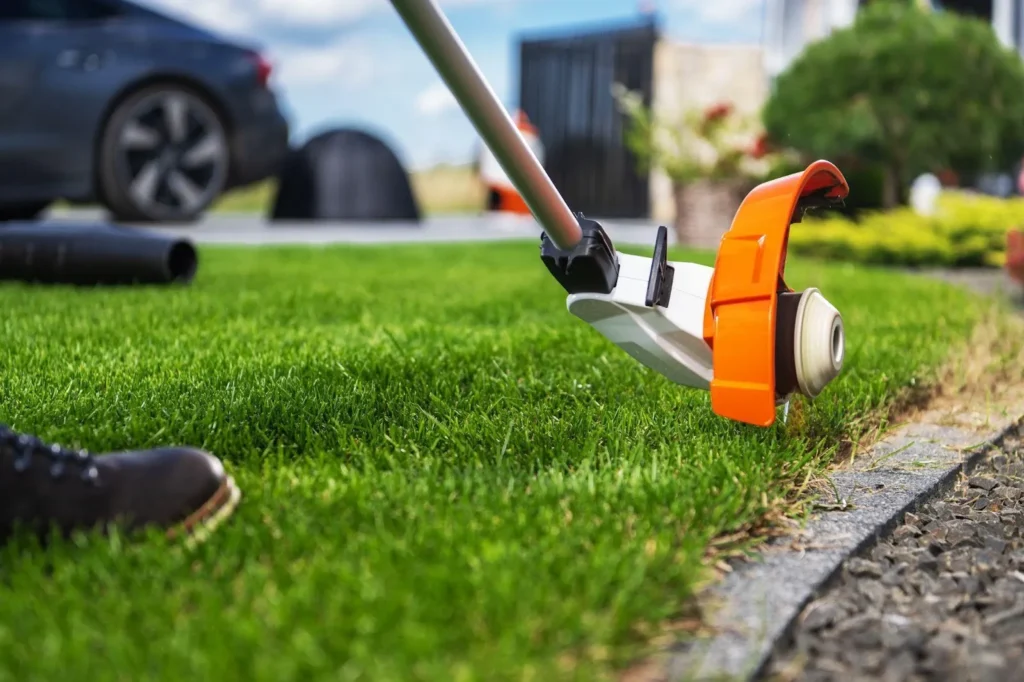 Trimming Lush Green Grass Along a Driveway