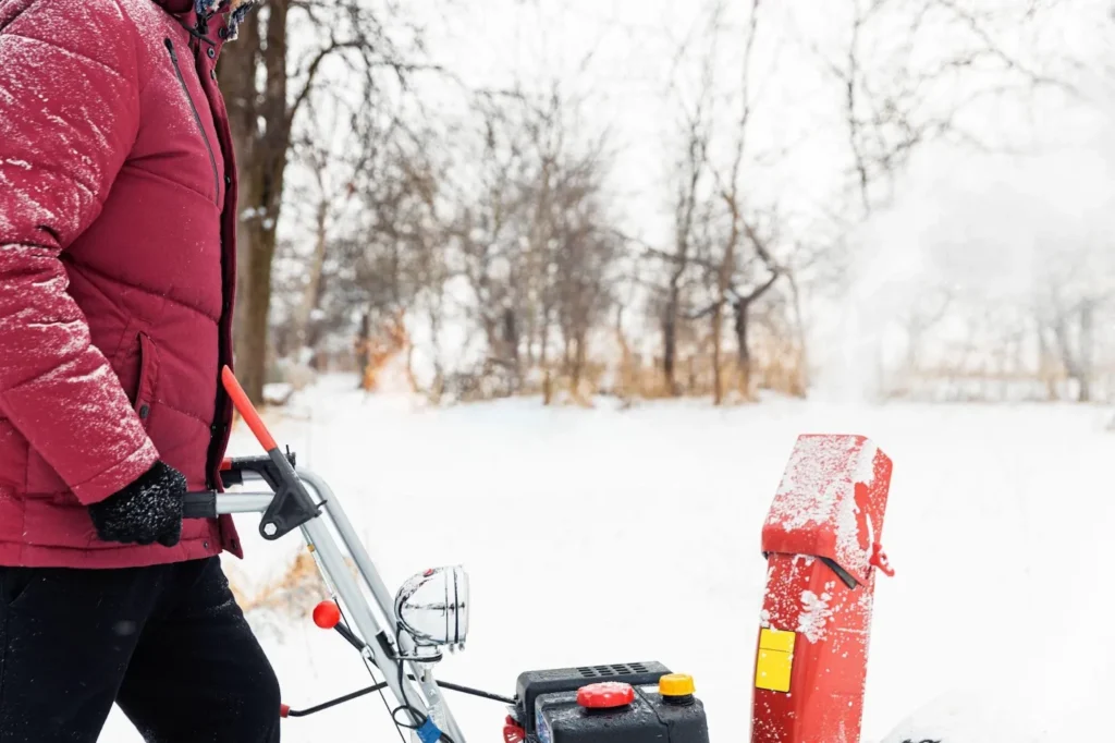 Man using a red snowblower machine outdoors to remove snow